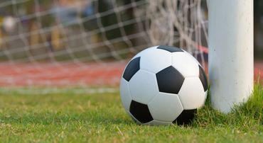 Soccer next to goalpost on green grass field